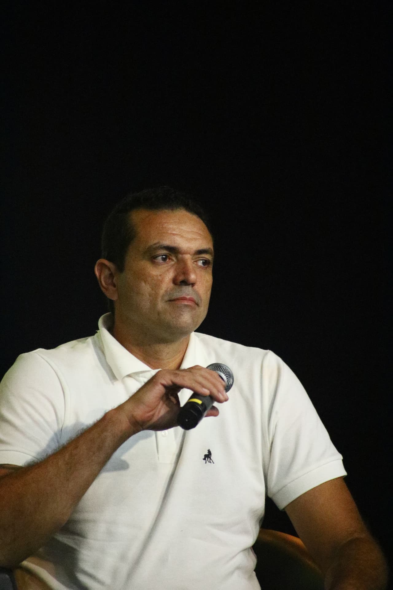 Douglas Campos falando ao microfone durante encontro do Consulado